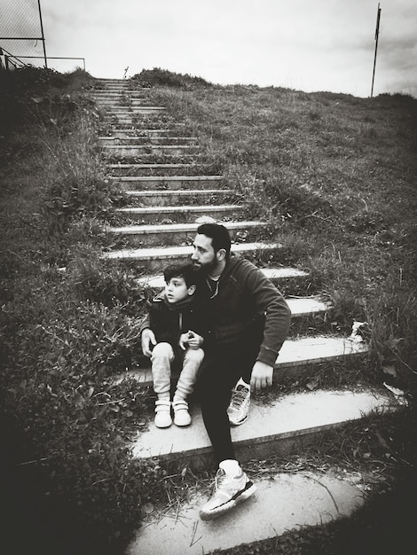 Photo close-up of father and son sitting on steps