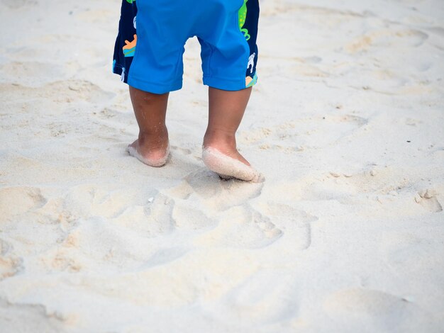 Close up feet of kid walking on the sand beachSand kid footprint