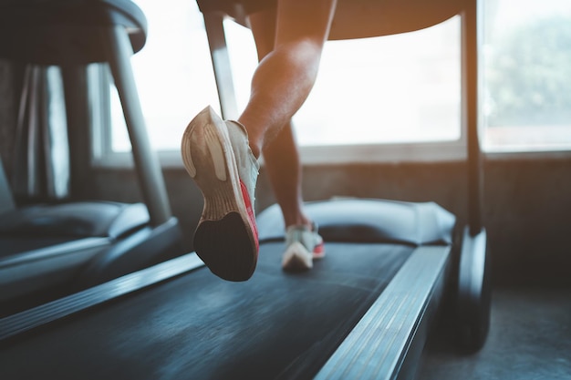 Close up of feet sportman runner running on treadmill in fitness club Cardio workout Healthy lifestyle guy training in gym Sport running concept