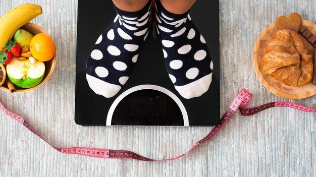 Close up of feet on a weight scale looking how much is her weight and if she has losed weight - healthy lifestyle and concept choice - choosing how to eat