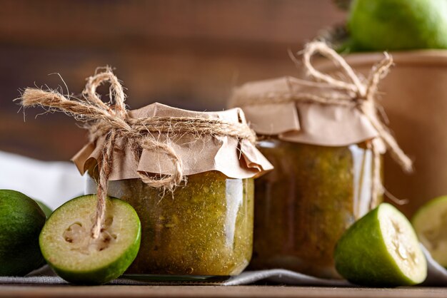 Close-up of feijoa jam in glass jars on brown wooden background