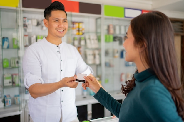 Close up of a female customer giving a credit card to a man for cashless payment