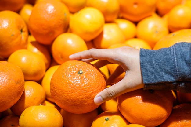 close up Female customer Hand pick up a fresh Orange in market