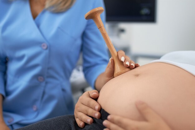 Close up of female doctor doing medical diagnostic of pregnant woman at modern clinic