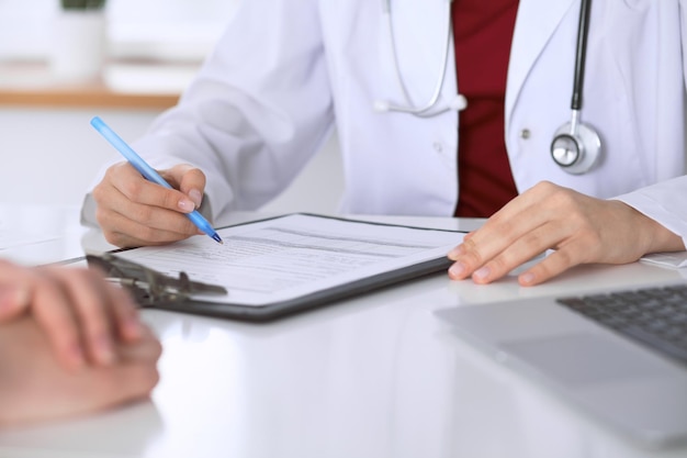 患者に相談しながら申請書に記入する女性医師のクローズアップ