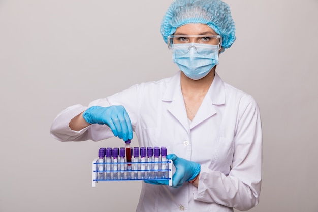 Close up female doctor hands with blood testing tube isolated on gray space