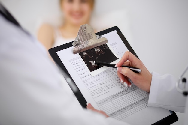 Close-up of a female doctor holding application form while consulting patient