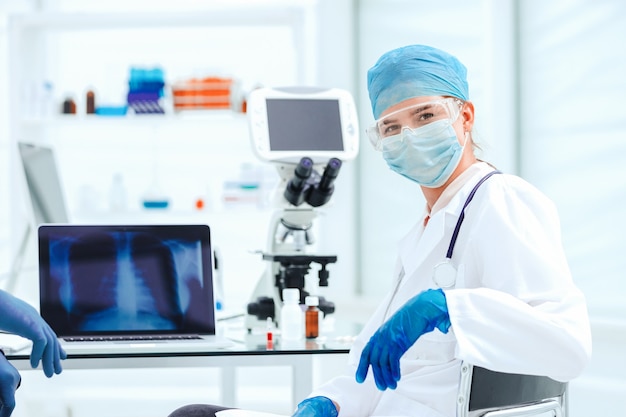 Close up. female doctor in a protective mask sitting at a laboratory table. concept of health care.