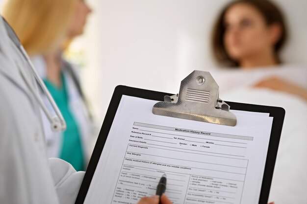 Close-up of a female doctor while filling up medical history record.