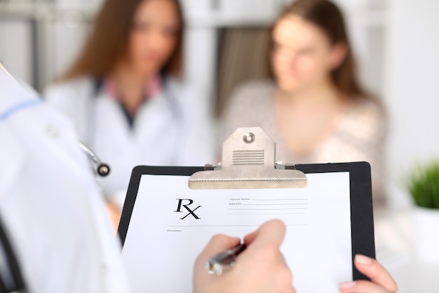 Close-up of a female doctor while filling up medical prescription.