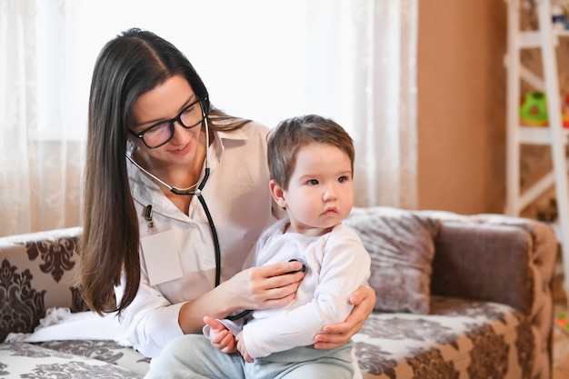 close up of female doctor with stethoscope listening to patient's heartbeat or breath at home