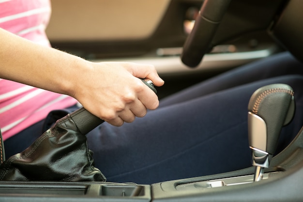 Close up of female driver hand holding hand brake in a car.