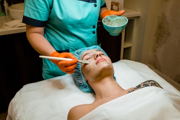 Photo close up of female face getting healthy clay mask by beautician