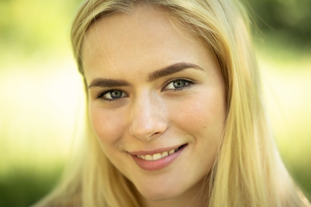 Primo piano del volto femminile, sorridente ragazza bionda in natura