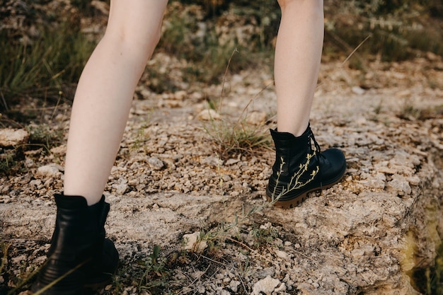 Close-up of female feet wearing black leather hiking boots,\
outdoors, in mountains, climbing on rocks.