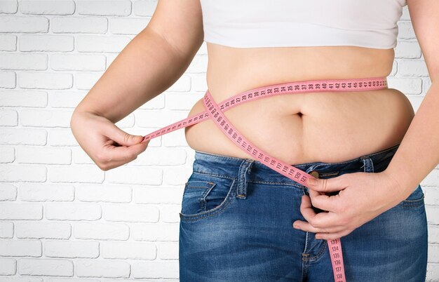 Close-up female figure with measuring tape on grey background