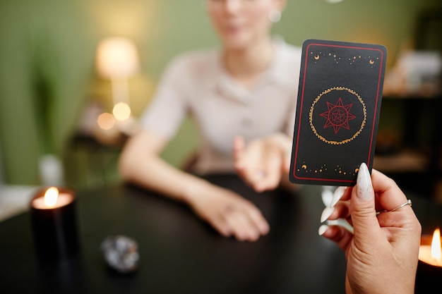 Close up of female fortune teller showing tarot cards for young\
woman visiting at spiritual seance copy space