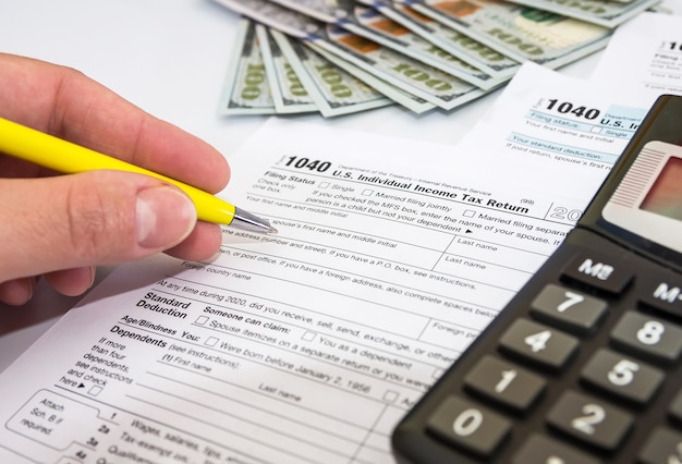 Close up of female hand fills out 1040 tax forms on white