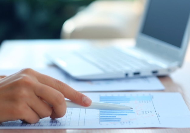 Close-up of female hand holding pen over business document