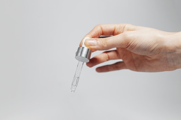 Close-up of female hand holding a pipette with cosmetic essential oil for skin care