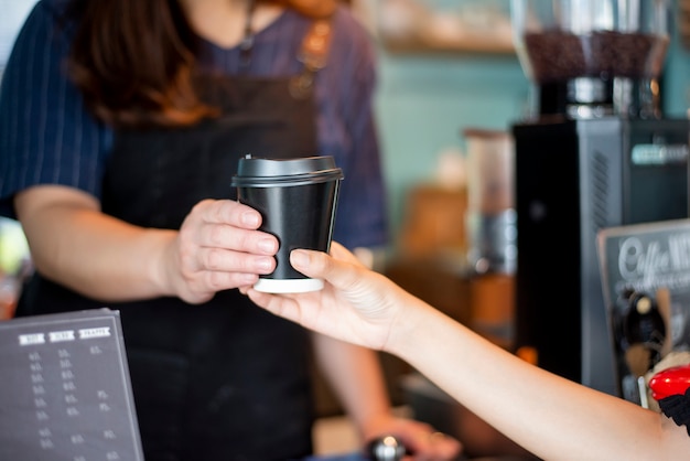 Close up of female hand is taking hot coffee from Barista 