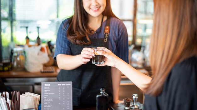 女性の手のクローズアップは、バリスタからホットコーヒーを取っています。