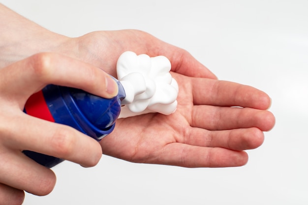 A close-up of a female hand squeezing foam in the palm of a hand from a blue balloon. Place soap foam with foam on hand.