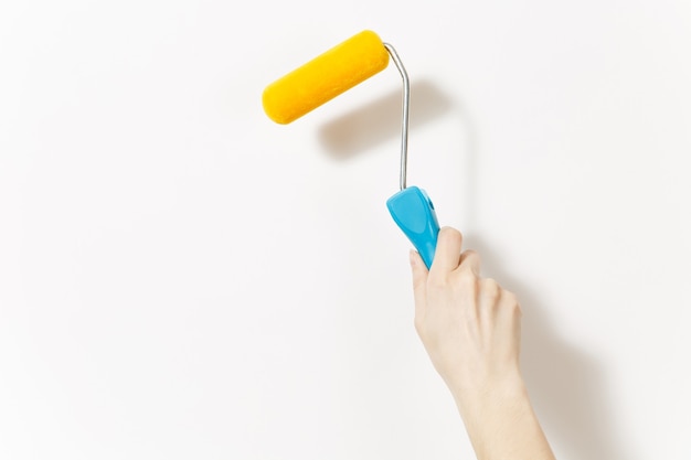 Close up of female hand vertical holds paint roller for wall painting isolated on white background. Instruments for renovation apartment room. Repair home concept. Copy space for advertisement.