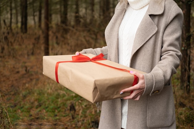 close up female hand with gift box in kraft paper packaging