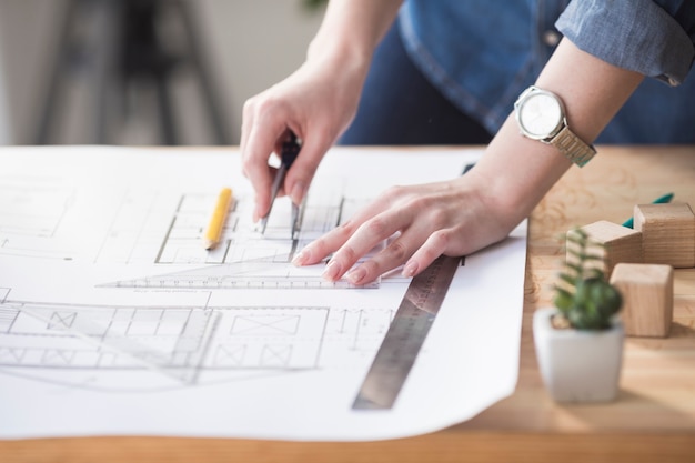 Photo close-up of female hand working on blueprint over wooden desk at workplace