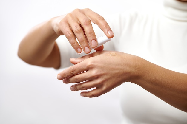 Primo piano delle mani femminili che applicano gel cosmetico trasparente sulle mani