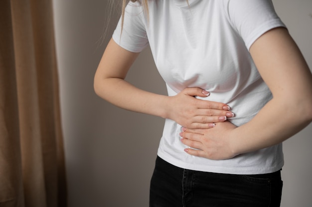 Close up of female hands on belly. Pain and colic during menstruation. Suffering and upset stomach