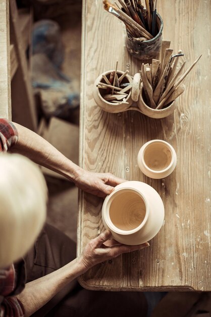 Close up of female hands examining ceramic bowl at workshop