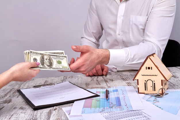 Close up female hands giving cash money to a realtor