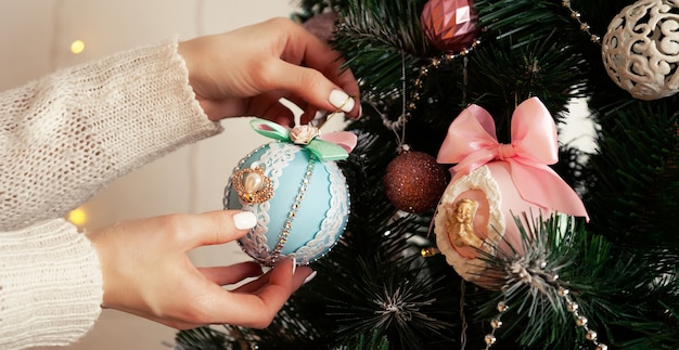 Close-up of female hands hang the ball on the tree