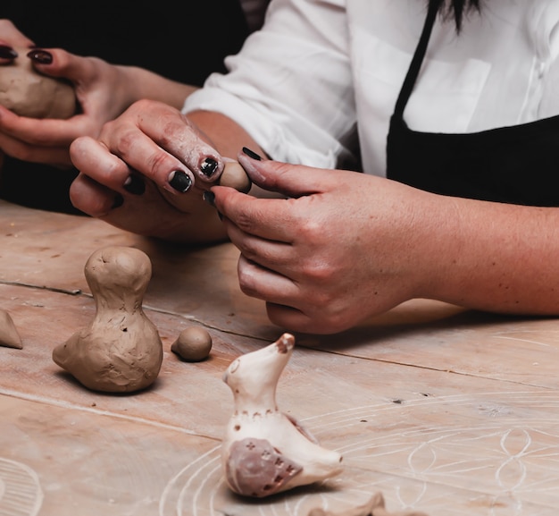 Close-up of female hands holding a ball made of clay