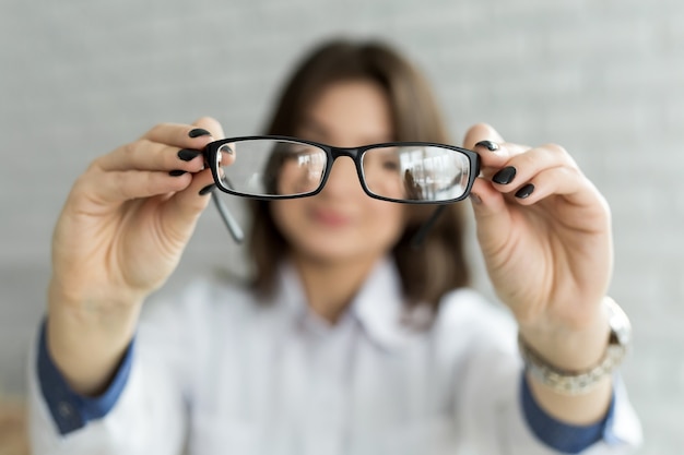 Close up female hands holding eyeglasses. Ophthalmology concept