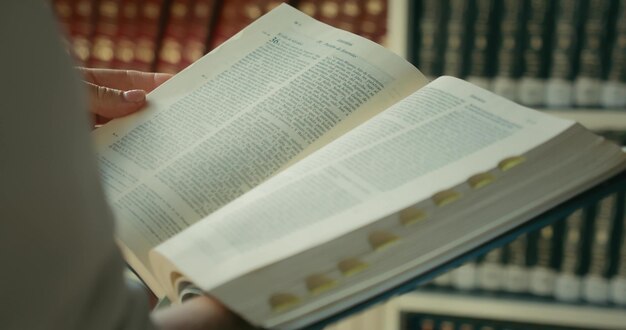 Close-up female hands holding and reading a book holy bible in public library theologian studies the history of the world search for truth