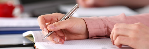 Close up female hands make an entry in diary note