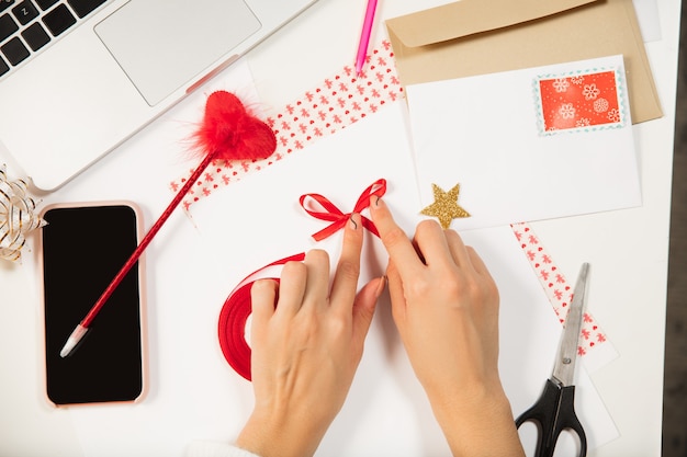 Close up female hands making greeting card for New Year and Christmas 2021 for friends or family