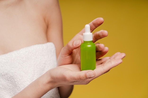 Close up of female hands model holding cosmetic jar isolated on yellow background in studio