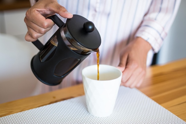 Close up of female hands pouring coffee from french press