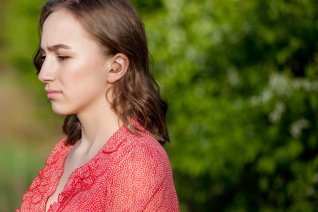 Close-up Of Female Hands Putting Hearing Aid In Ear. Modern digital in the ear hearing aid for deafness and the hard of hearing patients.