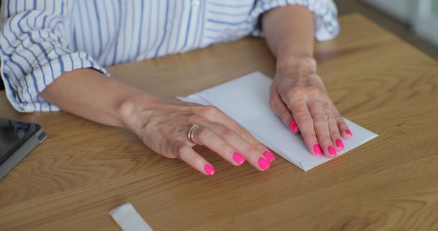 Close up female hands putting letter in envelop return form Woman sends a return form by letter