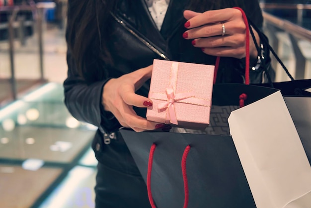 Close up of female hands putting little present into shopping paper bag Buying presents for Christmas and New Year Preparation of gifts for holidays Purchasing gifts for friends Beautiful pack