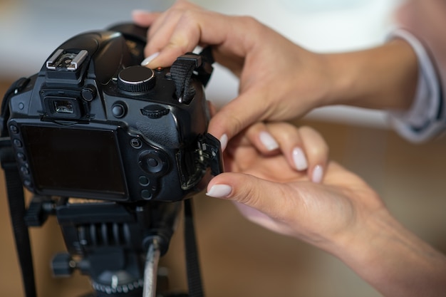 Foto primo piano di mani femminili che impostano la fotocamera mentre si prepara a sparare