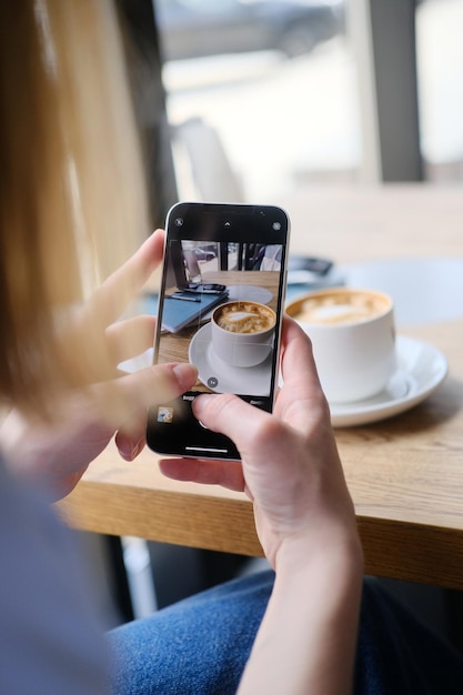 close up of female hands taking photo of coffee cup