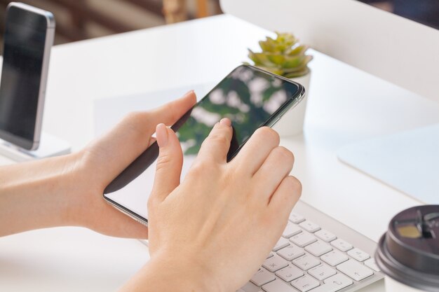 Close up of female hands using smartphone at office table