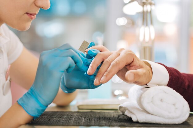 Close up of female hands wearing gloves and using file