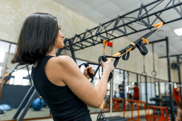 Close-up female hands with fitness straps in gym